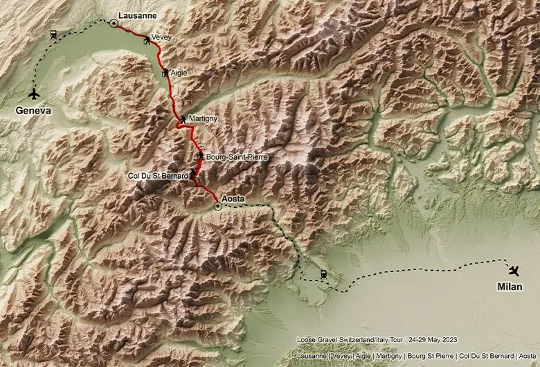 Shaded relief topographic map of a section of the Via Francigena between Switzerland and Italy. A bold red line highlights the route winding through rugged alpine terrain from Lausanne, passing through Vevey, Aigle, Martigny, Bourg-Saint-Pierre and Col Du St Bernard, down to Aosta. Dashed black lines indicate travel connections to Geneva and Milan, marked with airplane and train icons