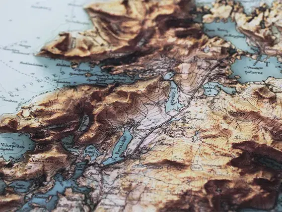 Close-up shot of a vintage cartographic print of Vestvågøya island in Norway, featuring 3D shaded relief showcasing mountains, fjords and contour lines